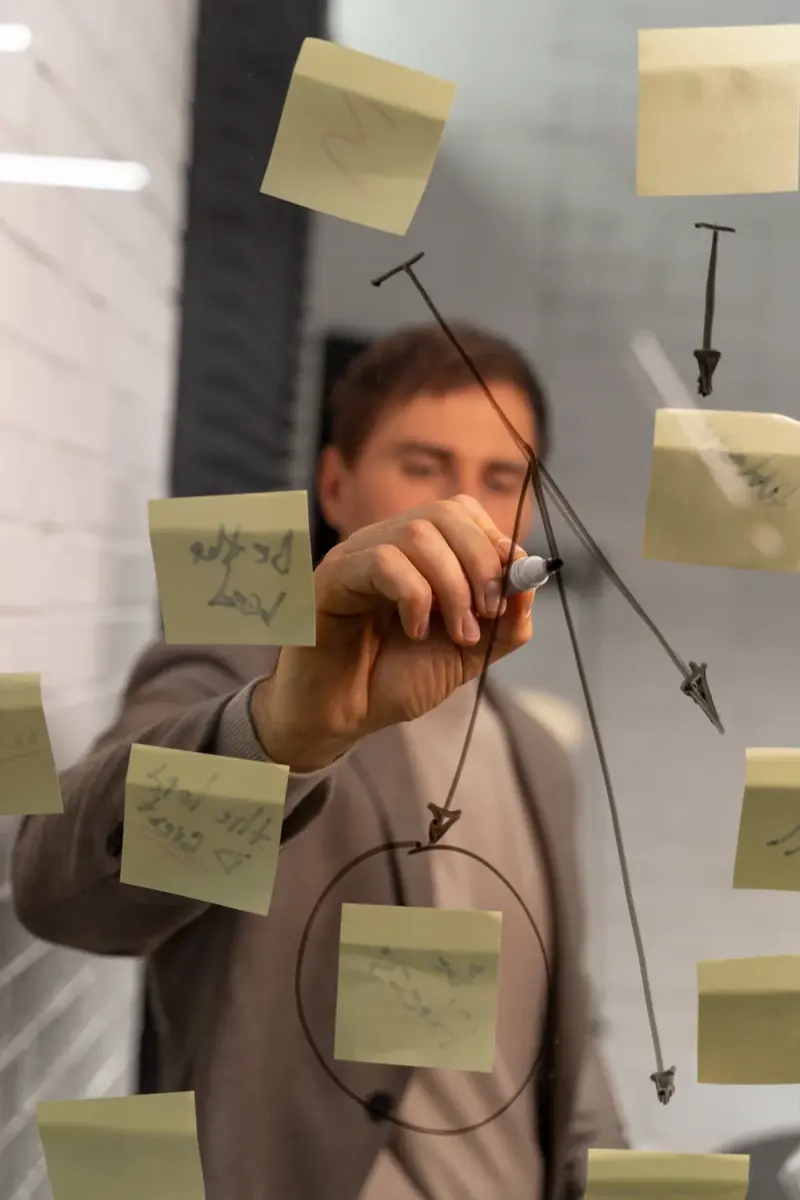 Persona organizando notas adhesivas sobre un vidrio