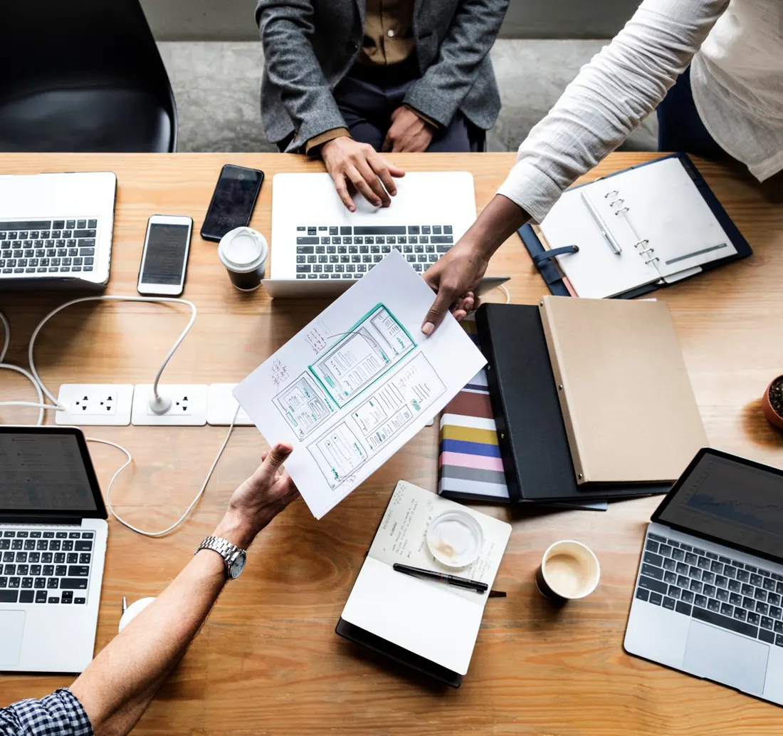 Equipo de trabajo compartiendo bocetos sobre una mesa