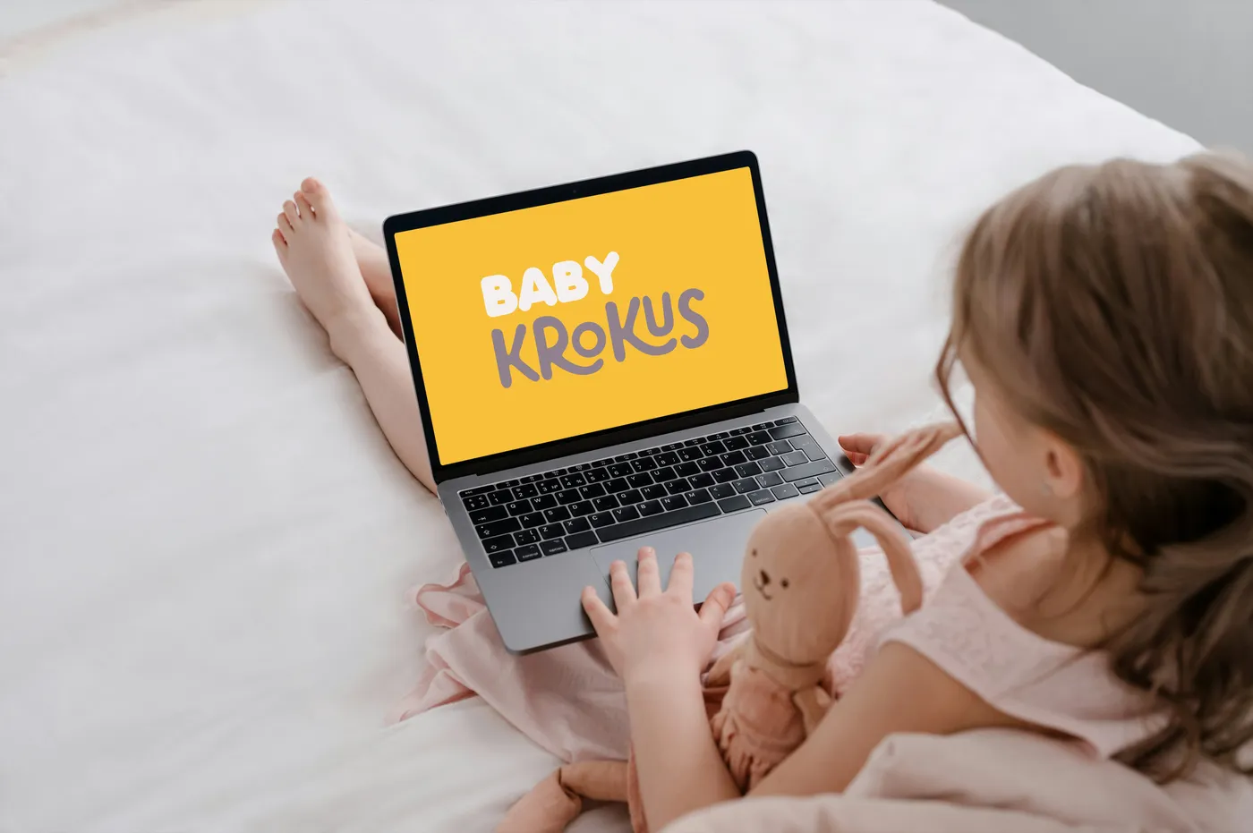Nena con una notebook que muestra el logo de una marca infantil